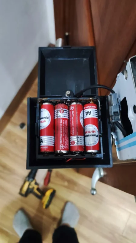 Bộ bốn pin AA trong khay khóa cửa có dấu ăn mòn ở thanh tiếp xúc